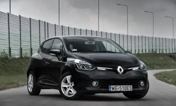 Czarny Renault Clio 4 z 2013 roku na drodze, z barierą dźwiękochłonną w tle.