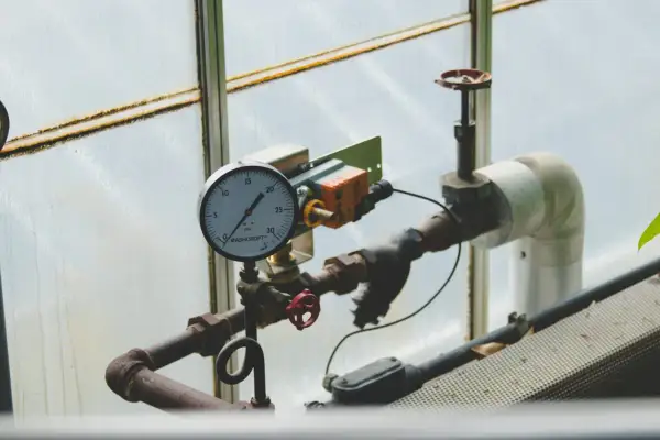 Manometr wskazuje niskie jakie ciśnienie na piecu gazowym. Rury i zawory są częścią instalacji.