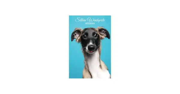 Un gracioso silken windsprite con la lengua afuera, posando para un cuaderno azul.