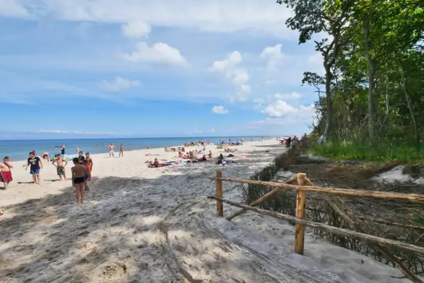 Słoneczny dzień na plaży w Karwieńskich Błotach. Ludzie odpoczywają na piasku, a morze wzywa do kąpieli.
