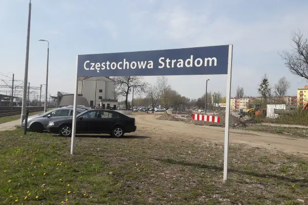 Tablica z napisem Częstochowa Stradom. W tle budynki, tory kolejowe i samochody.