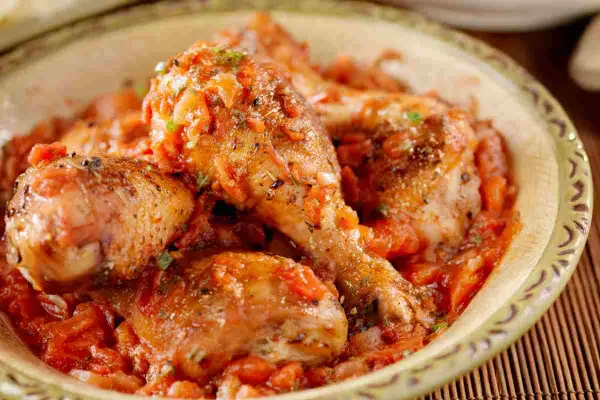 Pollo alla cacciatora ricetta della nonna: succulenti pezzi di pollo in un ricco sugo di pomodoro e erbe aromatiche, serviti in una ciotola rustica.