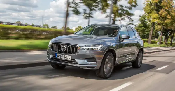 Szary Volvo XC60 T8 w ruchu, z rozmytym tłem drzew i nieba.