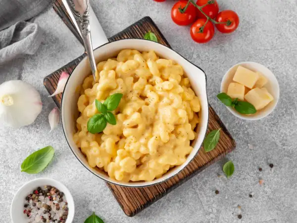 Pyszne, kremowe mac and cheese w białej misce, z bazylią i pomidorkami koktajlowymi. Idealne, gdy zastanawiasz się, jak podgrzać mac and cheese.