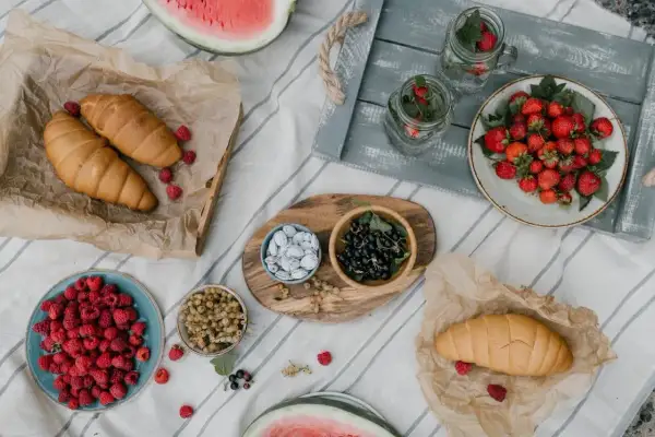 Letnie owoce i rogaliki na pikniku. Idealne na fit przepisy. Truskawki, maliny, porzeczki, arbuzy i napoje z miętą.