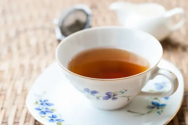 Aromaticzna herbata earl grey, znana ze swoich właściwości pobudzających i relaksujących, w eleganckiej filiżance z niebieskimi kwiatami.