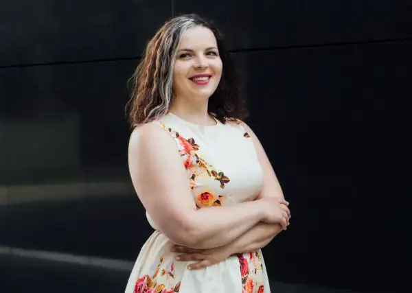 Uśmiechnięta kobieta w kwiecistej sukience, szukająca tanich sukienek plus size na wesele.
