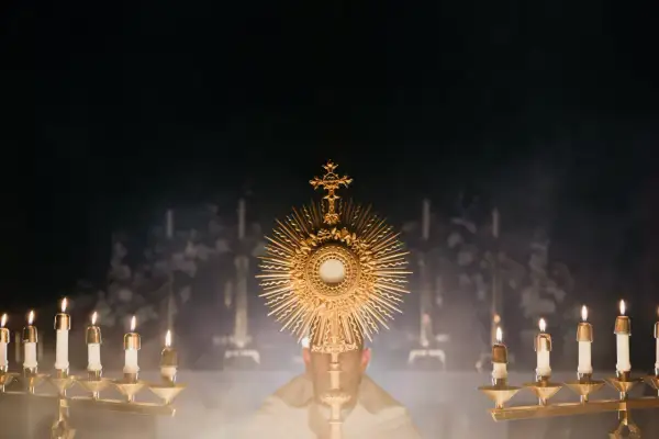 Złota monstrancja z hostią, otoczona płonącymi świecami, symbolizuje obecność Chrystusa. To obraz nawiązujący do 7 sakramentów świętych.