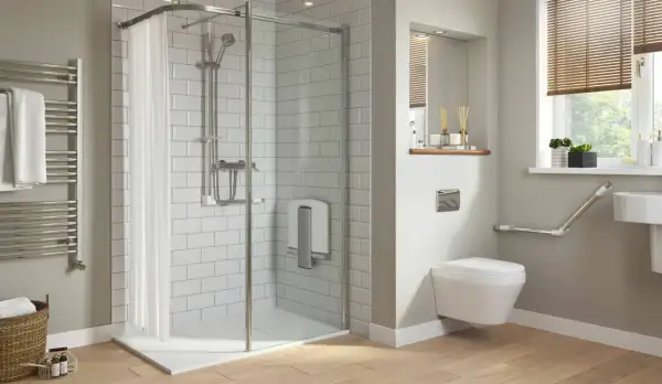 Salle de bain moderne avec douche de sol, carrelage blanc, porte-serviettes chauffant et WC suspendu avec barres d'appui.