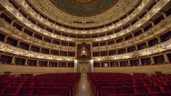 Interno di un teatro storico con file di poltrone rosse e palchi dorati. Un luogo da scoprire tra le cose da vedere a Parma gratis.