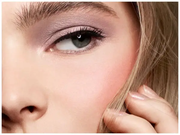 Un occhio truccato con ombretto rosa e un tocco di blush sulle guance, che dona un aspetto sano e radioso.