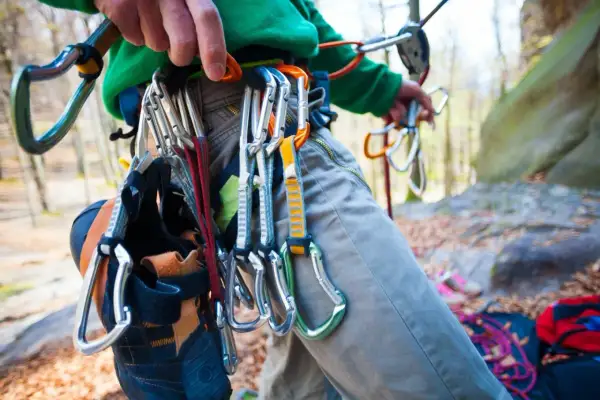 Kletterer mit Ausrüstung, darunter Kletterschuhe und Karabiner, bereit für die selbstsicherung beim Klettern.