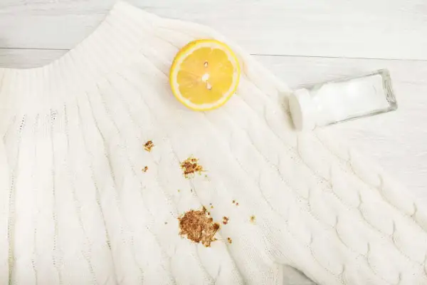 Maglione bianco con macchia di ruggine. Limone e sale pronti per rimuoverla.