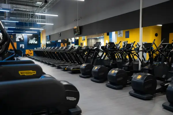 Rzędy bieżni i orbitreków w siłowni Just Gym. Dowiedz się, jak wejść na Multisport i zacząć trening.