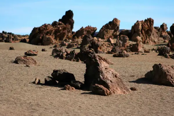 Paisaje desértico con rocas volcánicas rojizas y arena, evocando la zona de las minas de San José.