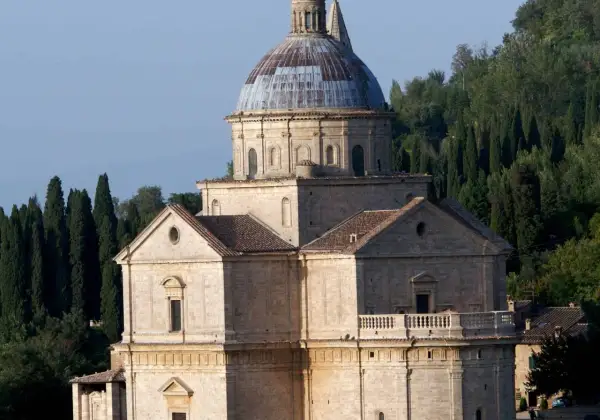 Il tempio di San Biagio, con la sua imponente cupola e la facciata in pietra, si erge maestoso tra i cipressi toscani.