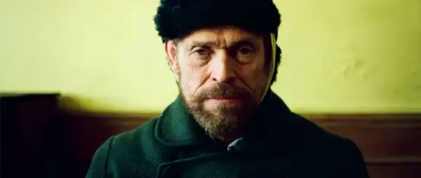 Willem Dafoe w czapce z futra i ciemnym płaszczu, w kadrze z filmu.