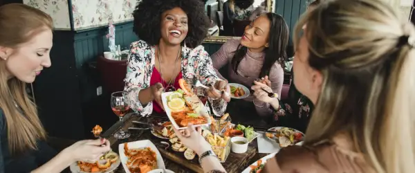 Vier Freundinnen genießen einen köstlichen Brunch in Berlin. Sie lachen und teilen sich Speisen wie Garnelen und Pommes.