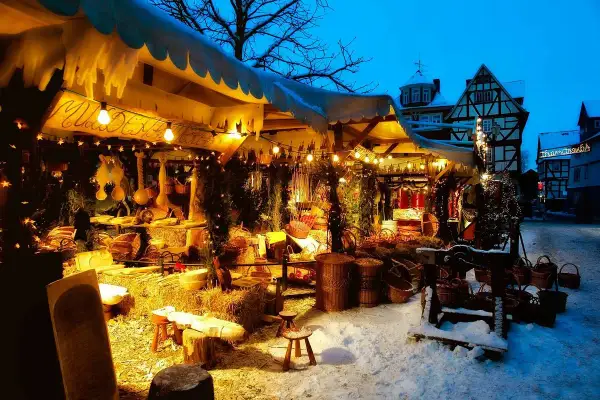 Winterliche Kirmes Gummersbach: Ein festlich beleuchteter Stand mit Körben und Holzwaren im Schnee.