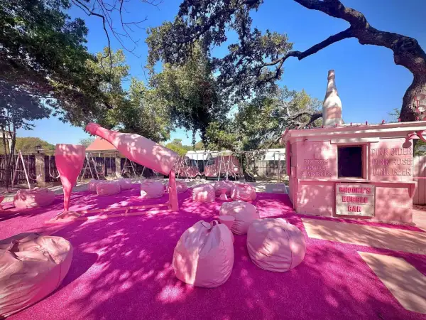 Różowa strefa relaksu z gigantyczną butelką i kieliszkiem prosecco rose, gdzie można usiąść na pufach i napić się różowego napoju.