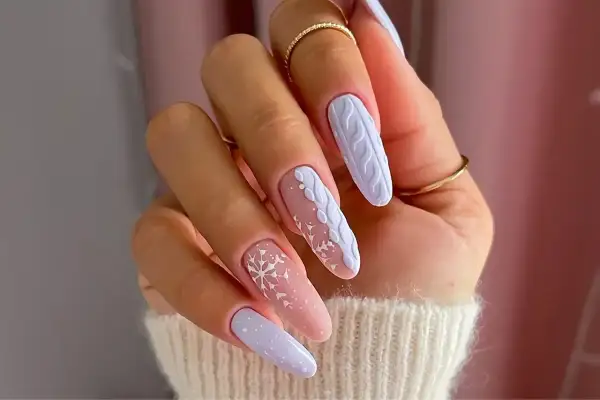 Manucure d'hiver avec des flocons de neige et un motif de pull tricoté sur des ongles longs. Un modèle ongle hiver parfait pour la saison.