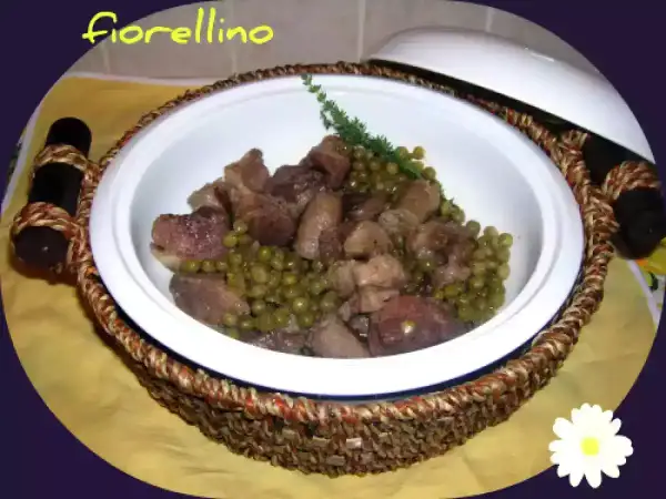 Un invitante spezzatino di maiale con piselli, servito in una ciotola bianca con manici intrecciati.