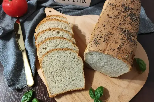 Domowy chleb pieczony w piekarniku, posypany makiem, pokrojony w kromki. Idealny przepis na pyszny, świeży bochenek.