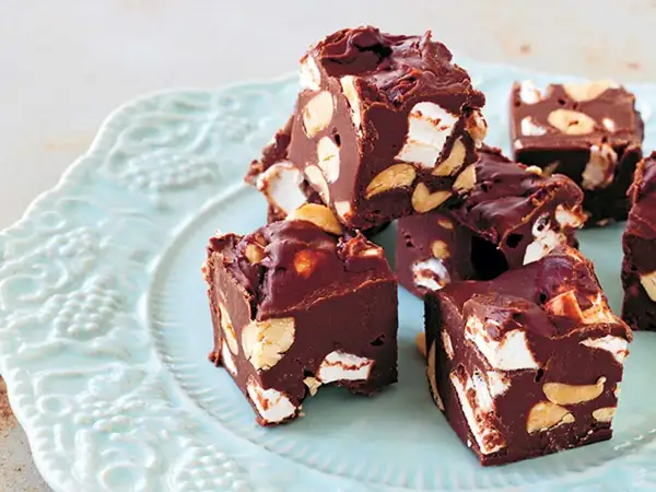 Chokladbitar med marshmallows och nötter, en härlig rocky road-fudge på en ljusblå tallrik.