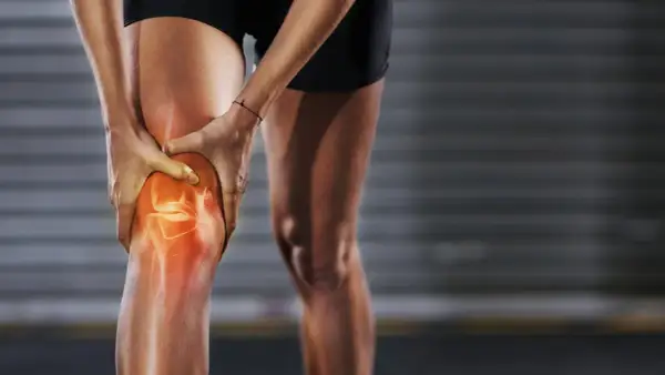 Eine Person hält ihr Knie, das rot leuchtet, um **Schmerzen unter der Kniescheibe** zu symbolisieren.