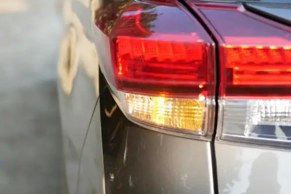 Gros plan sur le feu arrière d'une voiture, le clignotant jaune est allumé, prêt à indiquer un changement de direction.