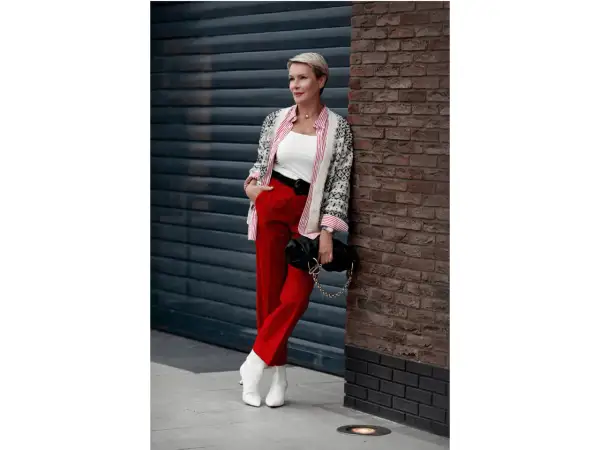 Elegancka kobieta w czerwonych spodniach i wzorzystym kardiganie, prezentująca stylowe czerwone spodnie stylizacje.
