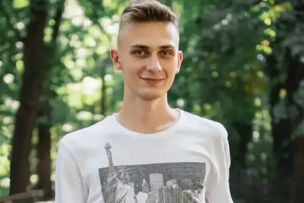 Uśmiechnięty nastolatek w białej koszulce z widokiem na Nowy Jork. Może to być przykład, jak zespół Aspergera objawy u nastolatków mogą być subtelne.
