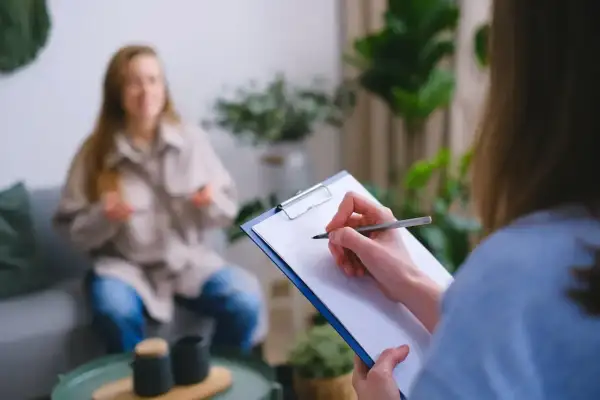 Psycholog policyjny zarobki: sesja terapeutyczna z pacjentem, notatki na kartce.