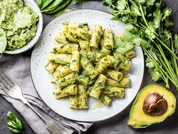 Makaron z pesto ze słoika, podany na talerzu, z awokado i świeżymi ziołami.