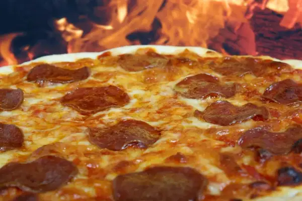 Pyszna pepperoni pizza z ciągnącym się serem, pieczona w ogniu.