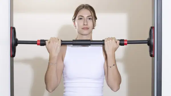 Frau hält Klimmzugstange Türrahmen Test. Einfache Montage für das Training zu Hause.