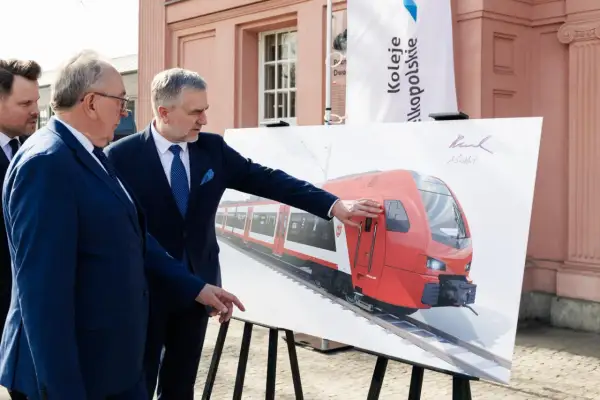 Dwóch mężczyzn w garniturach ogląda wizualizację nowego pociągu Kolei Wielkopolskich. Nowe połączenia Poznań - Nowy Tomyśl wkrótce!