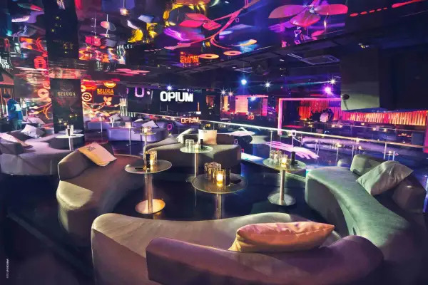 Interni lussuosi della discoteca Opium a Barcellona, con divani curvi, tavolini di vetro e luci al neon che creano un'atmosfera vibrante.