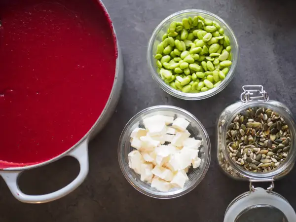 Röd soppa i gryta, edamamebönor, ost och fröblandning. Enkla ingredienser för att leva billigt mat.