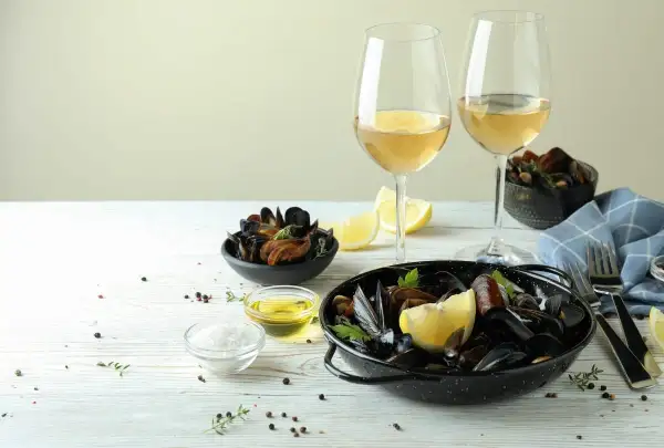 Ein festliches Essen: Muscheln mit Zitrone und Kräutern, dazu ein Glas Weißwein. Perfekt für einen genussvollen Abend.