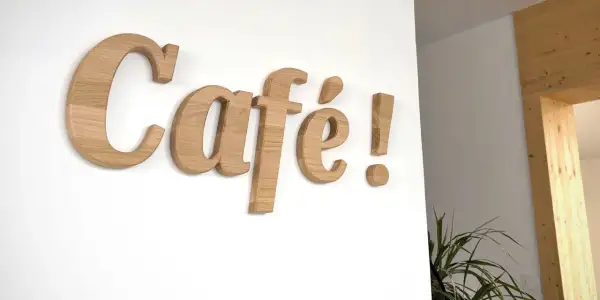 Lettre en bois "Café !" sur un mur blanc. Ces lettres en bois, comme une lettre PVC, apportent une touche chaleureuse.