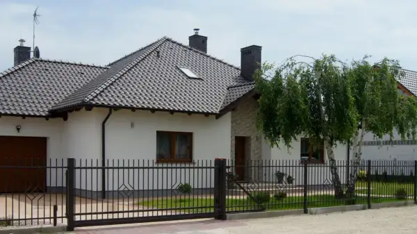 Nowy, nowoczesny dom z czarnym, metalowym ogrodzeniem. Czy to ogrodzenie bez pozwolenia?