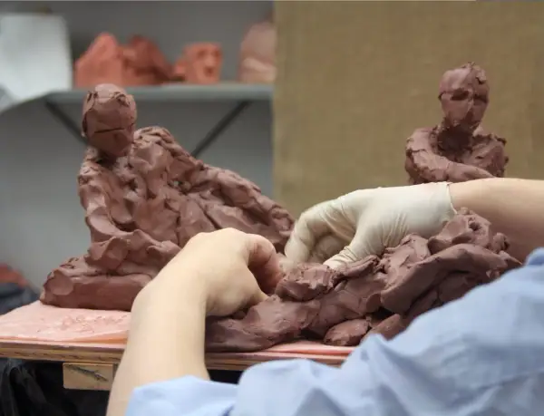 Hands sculpt clay figures, a glimpse into the dedication needed for the best sculpture schools.
