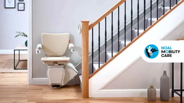Installazione montascale beige su una scala con corrimano in legno e ringhiera nera. La soluzione ideale per la mobilità in casa.