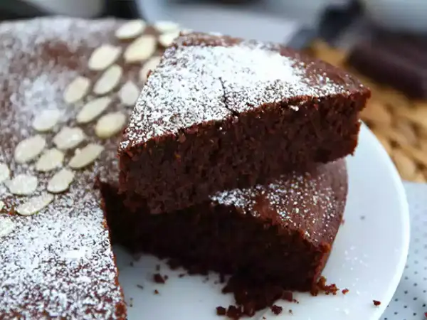 En saftig torta caprese, pudrad med florsocker och garnerad med mandelspån. En dröm för chokladälskare!