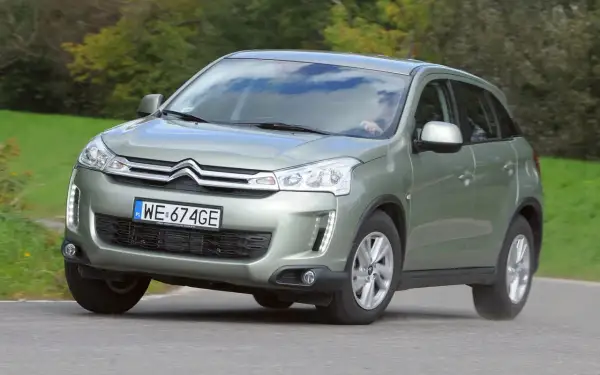 Zielony Citroen C4 Aircross z polskimi tablicami WE 674GE jedzie po drodze wśród zieleni.