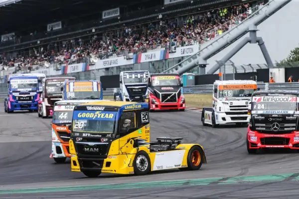 Des camions de course colorés s'affrontent lors d'un grand prix camion, sous les yeux d'une foule en délire dans les tribunes.