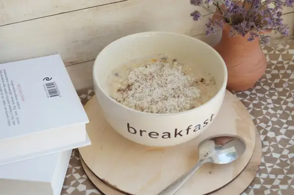 Misternie przygotowana owsianka na śniadanie, a obok książka. Czy płatki owsiane mają gluten? To pytanie nurtuje wielu.