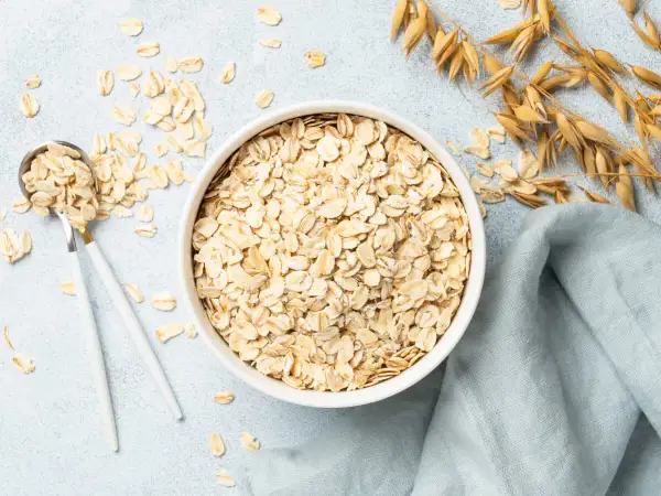 Misternie ułożone płatki owsiane w misce i na łyżce. Czy płatki owsiane mają gluten? Zwykłe płatki owsiane nie zawierają glutenu, ale mogą być zanieczyszczone podczas przetwarzania.