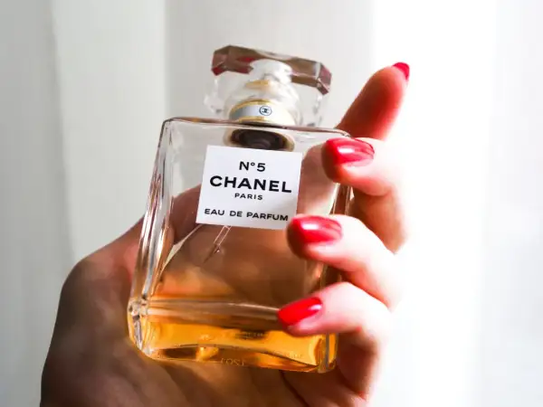Dłoń z czerwonymi paznokciami trzyma flakonik Chanel N°5 100ml.